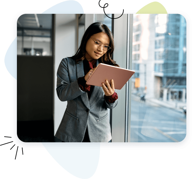 Lady looking on tablet smiling in front of a window